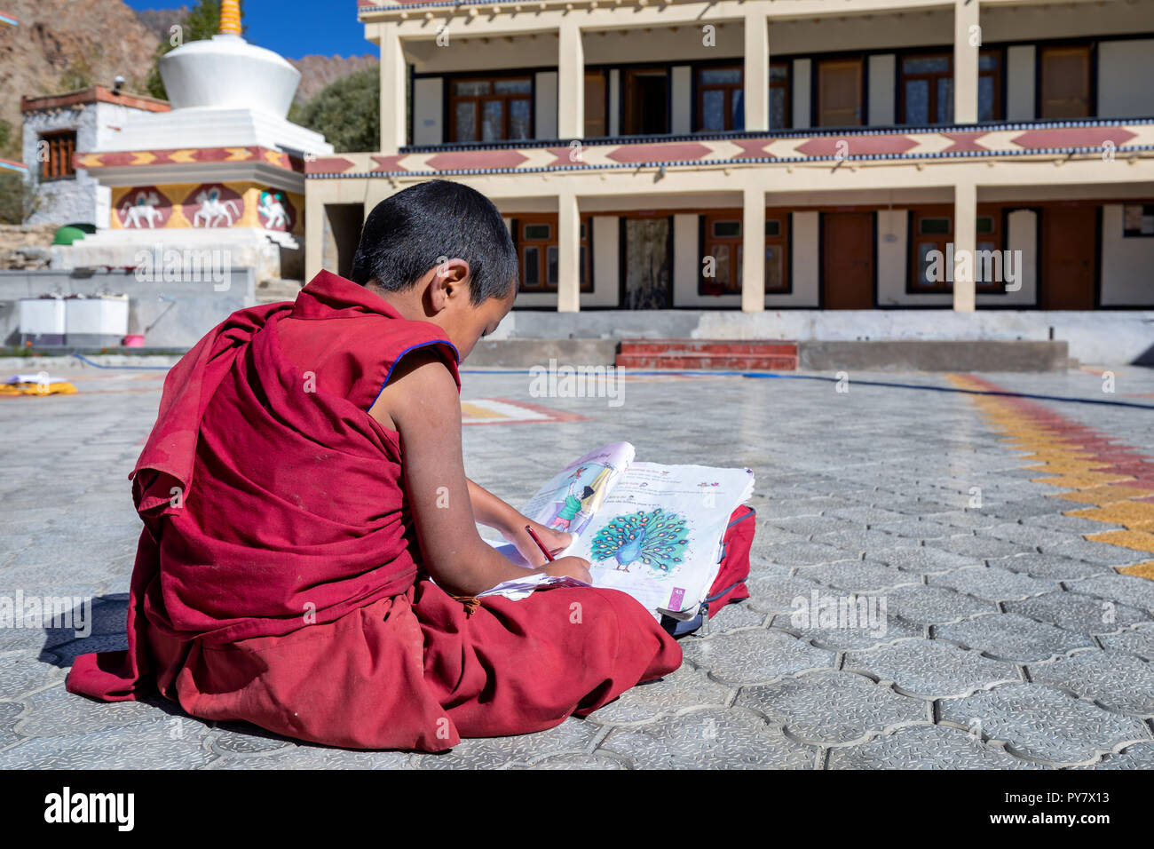 Ein kleiner Schuljunge, der draußen im Likir Kloster oder Likir Gompa, Ladakh, Indien, sitzt Stockfoto