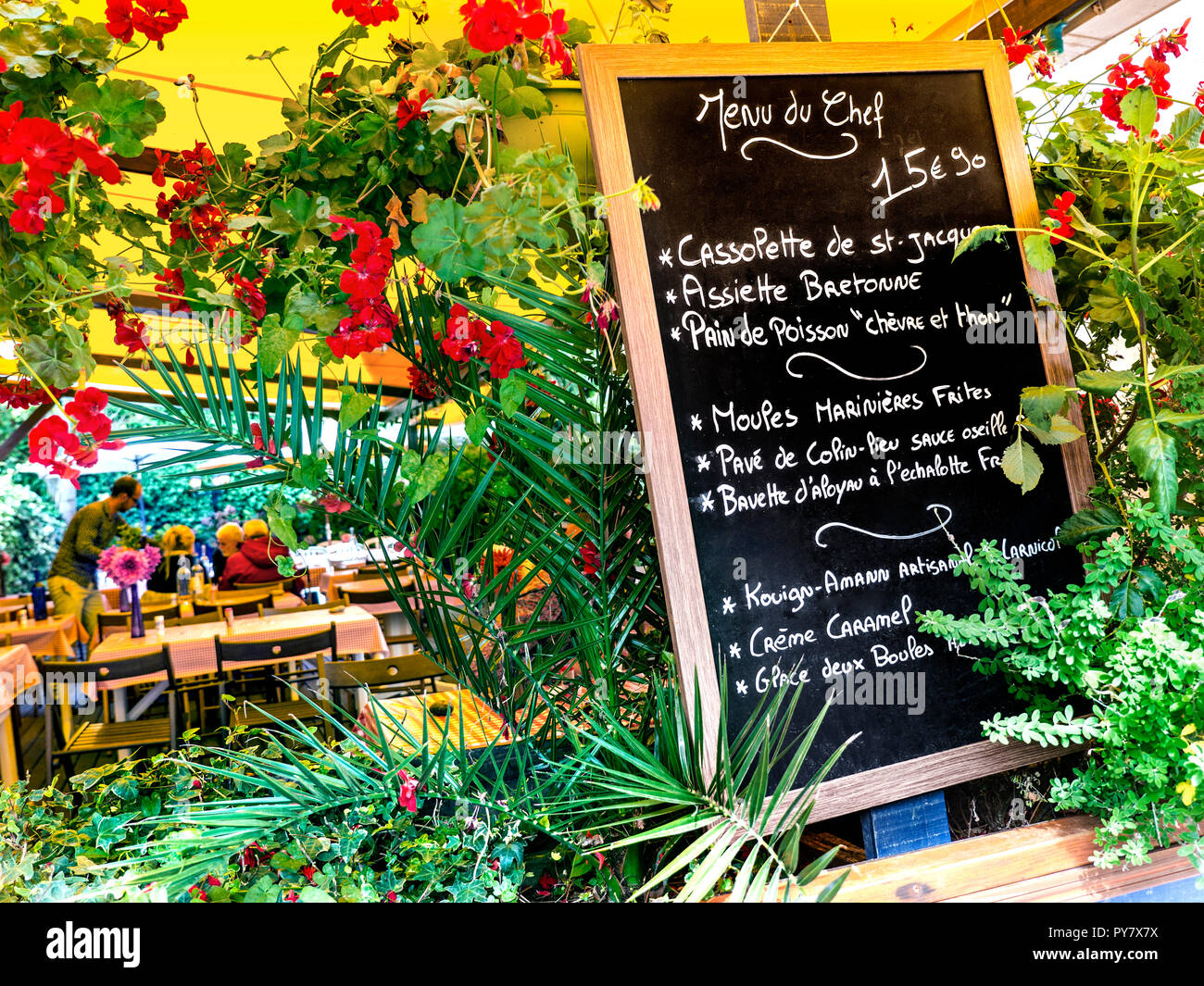Französische florale Tafel Menü des Tages Menu du Chef" mit Bedienung am Tisch hinter der typischen rustikalen französischen Restaurant in Concarneau Bretagne Frankreich Stockfoto