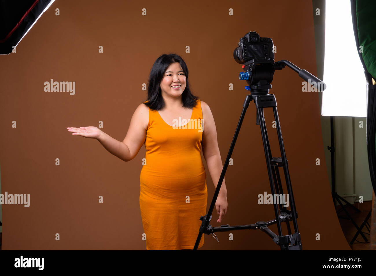 Schöne übergewichtige Frau vlogging im Studio mit DSLR-Kamera auf Stativ Stockfoto
