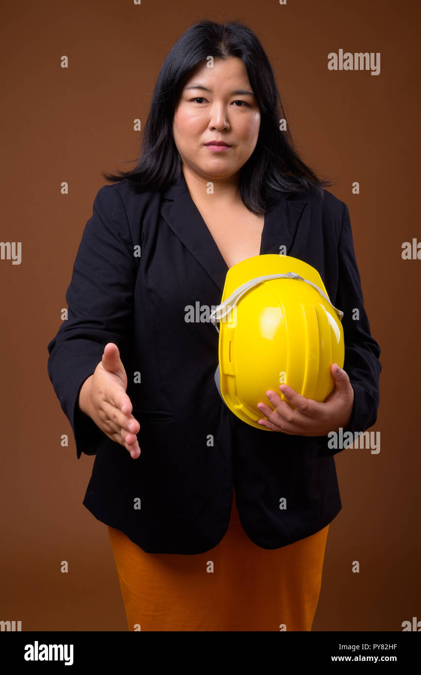 Asiatische Geschäftsfrau Holding hardhat und Handshake Stockfoto