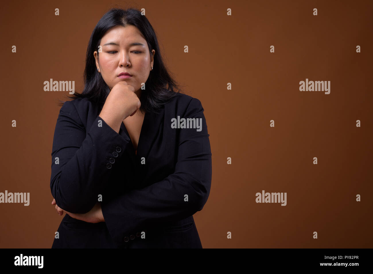 Betonte Übergewicht asiatischen Geschäftsfrau denken und nach unten schauen. Stockfoto