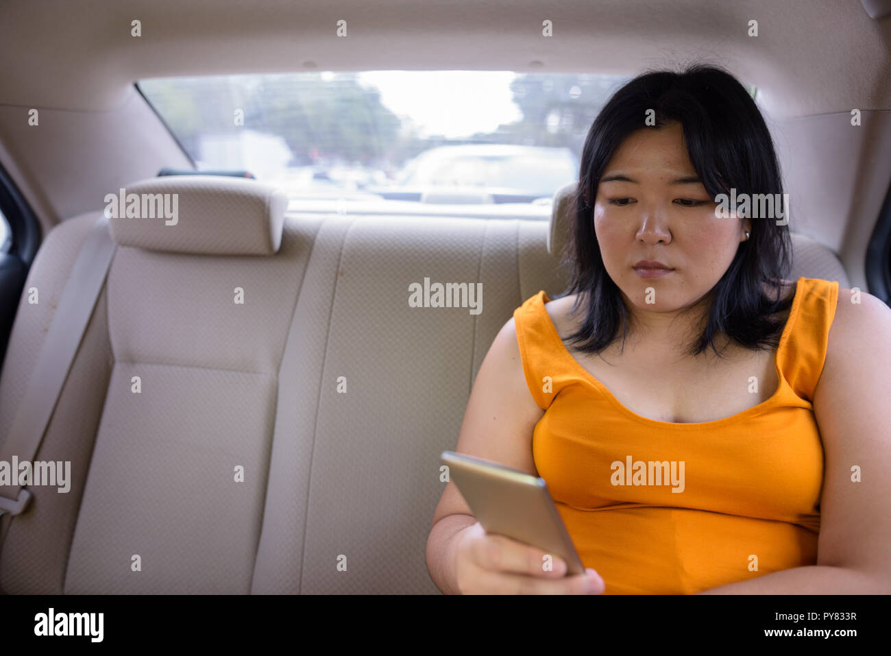 Schöne Übergewicht asiatische Frau mit Handy im Auto Stockfoto