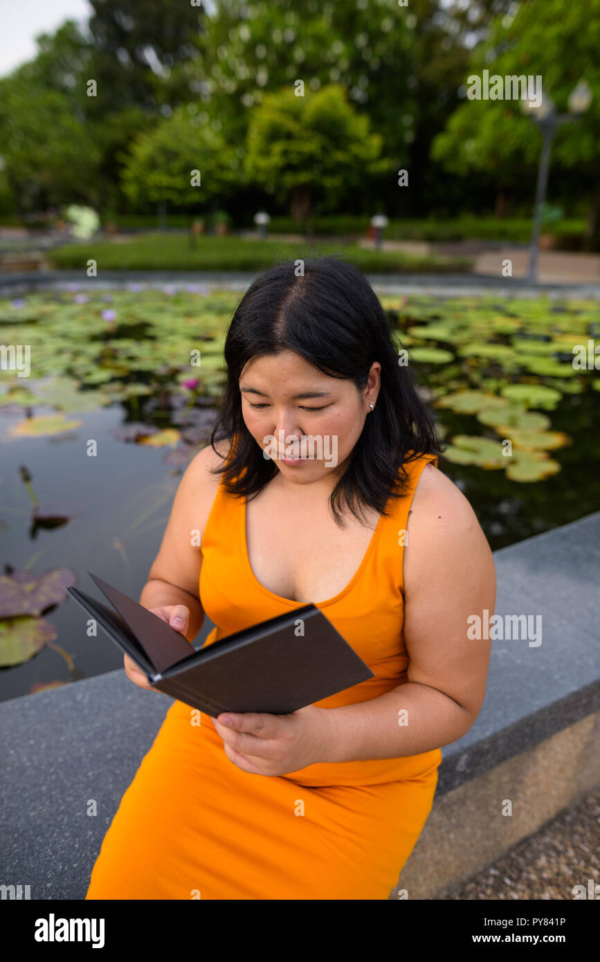 Schöne Übergewicht asiatische Frau Lesung buchen Sie im Park Stockfoto