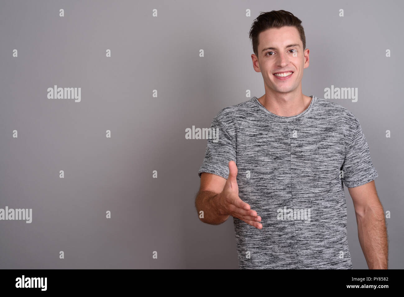 Jungen gutaussehenden Mann, der Händedruck und Kamera Stockfoto