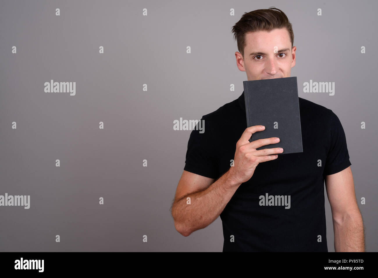 Junge hübsche Studentin Mann hinter Buch ausblenden Stockfoto