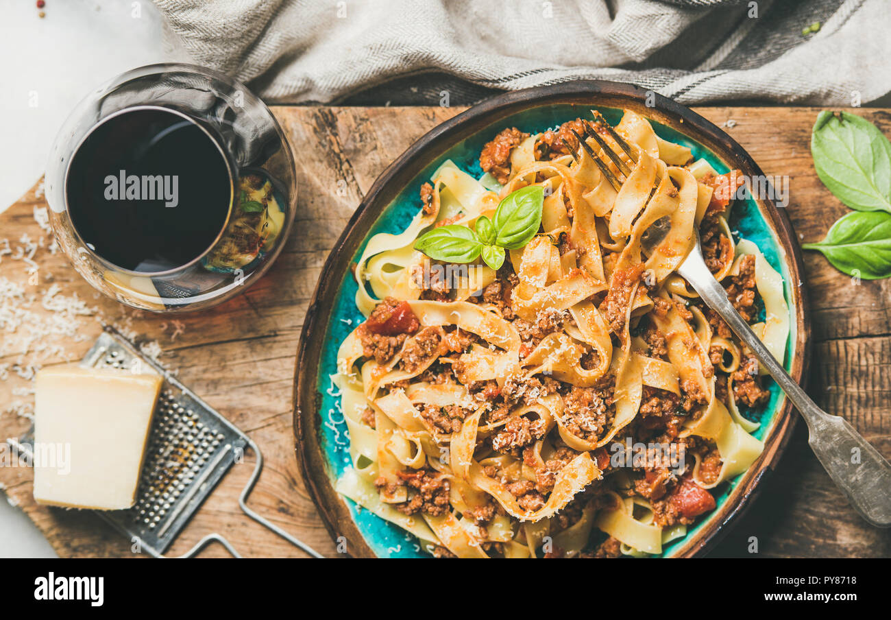 Traditionelle Pasta italienisches Abendessen. Flachbild-lay von Tagliatelle bolognese mit Hackfleisch, Tomatensauce und geriebenen Parmesan und einem Glas Rotwein ov Stockfoto