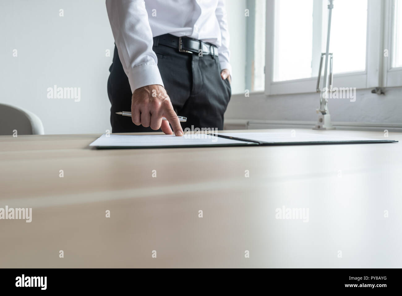 Geschäftsmann, der an seinem Schreibtisch, der auf ein Dokument im Ordner, wo zu unterzeichnen. Stockfoto
