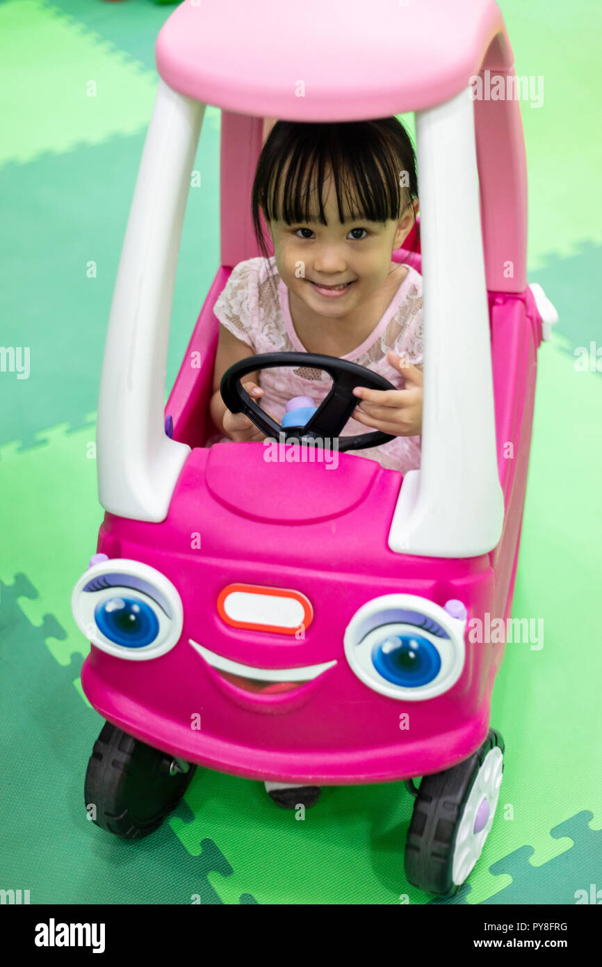 Asiatische chinesische Mädchen fahren Spielzeug Auto an Indoor Spielplatz Stockfoto