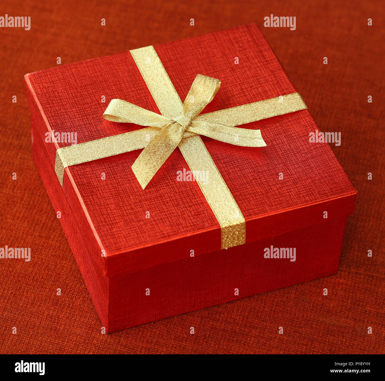 Roter Geschenkbox mit Schleife binden auf roten Hintergrund Tuch Stockfoto