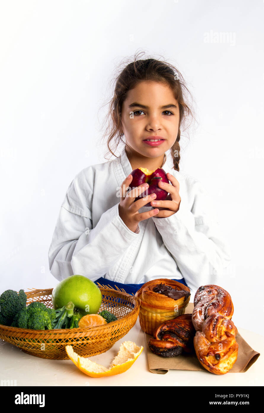 Ein kleines Mädchen in Karate uniform und eine Blue Belt wählte Äpfel anstelle von Brötchen essen Stockfoto
