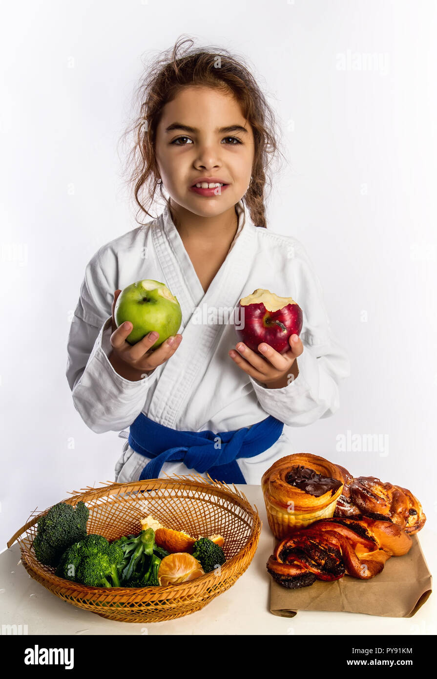 Ein kleines Mädchen in Karate uniform und eine Blue Belt wählte Äpfel anstelle von Brötchen essen. Stockfoto