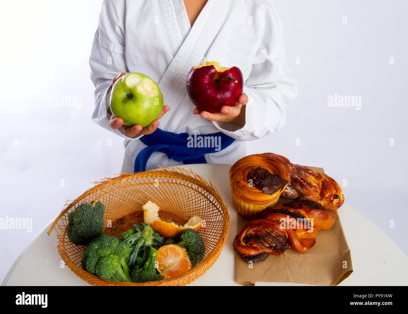 Ein kleines Mädchen in Karate uniform und eine Blue Belt wählte Äpfel anstelle von Brötchen essen. Stockfoto