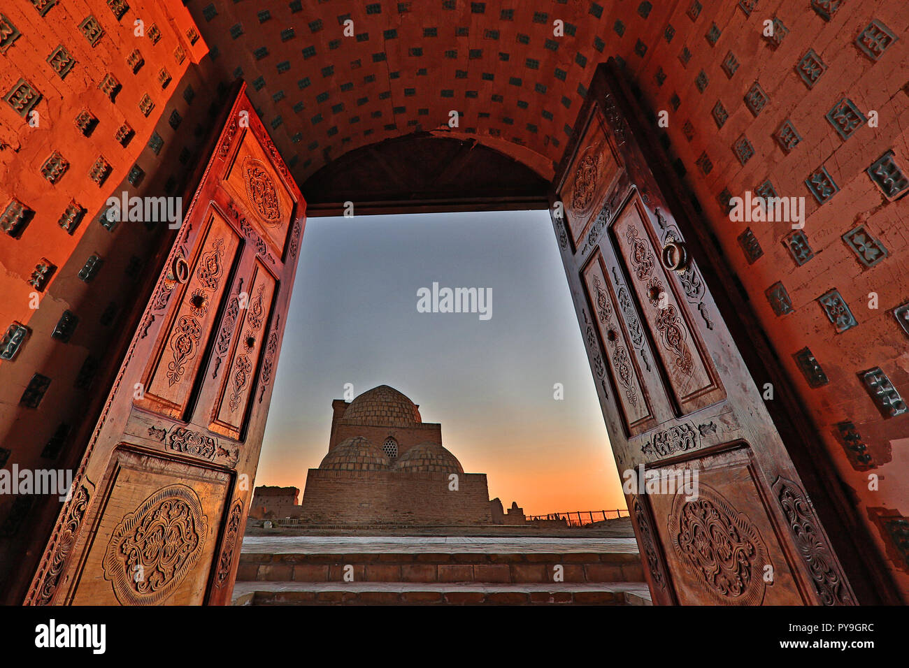 Blick über die mausolem durch hölzerne Türen an den Sonnenuntergang, in der Alten Friedhof von Mizdakhan in Hauptstadt-territorium, Usbekistan Stockfoto