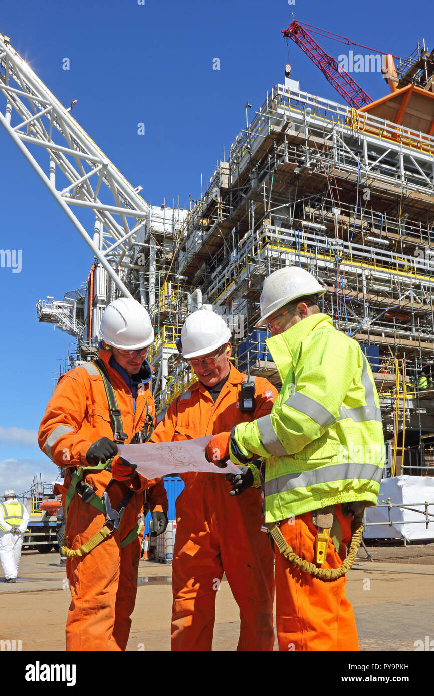 3 Ingenieure discus eine Zeichnung beim Bau eines Offshore Plattform in der Nordsee Hafen von Hartlepool, Großbritannien Stockfoto