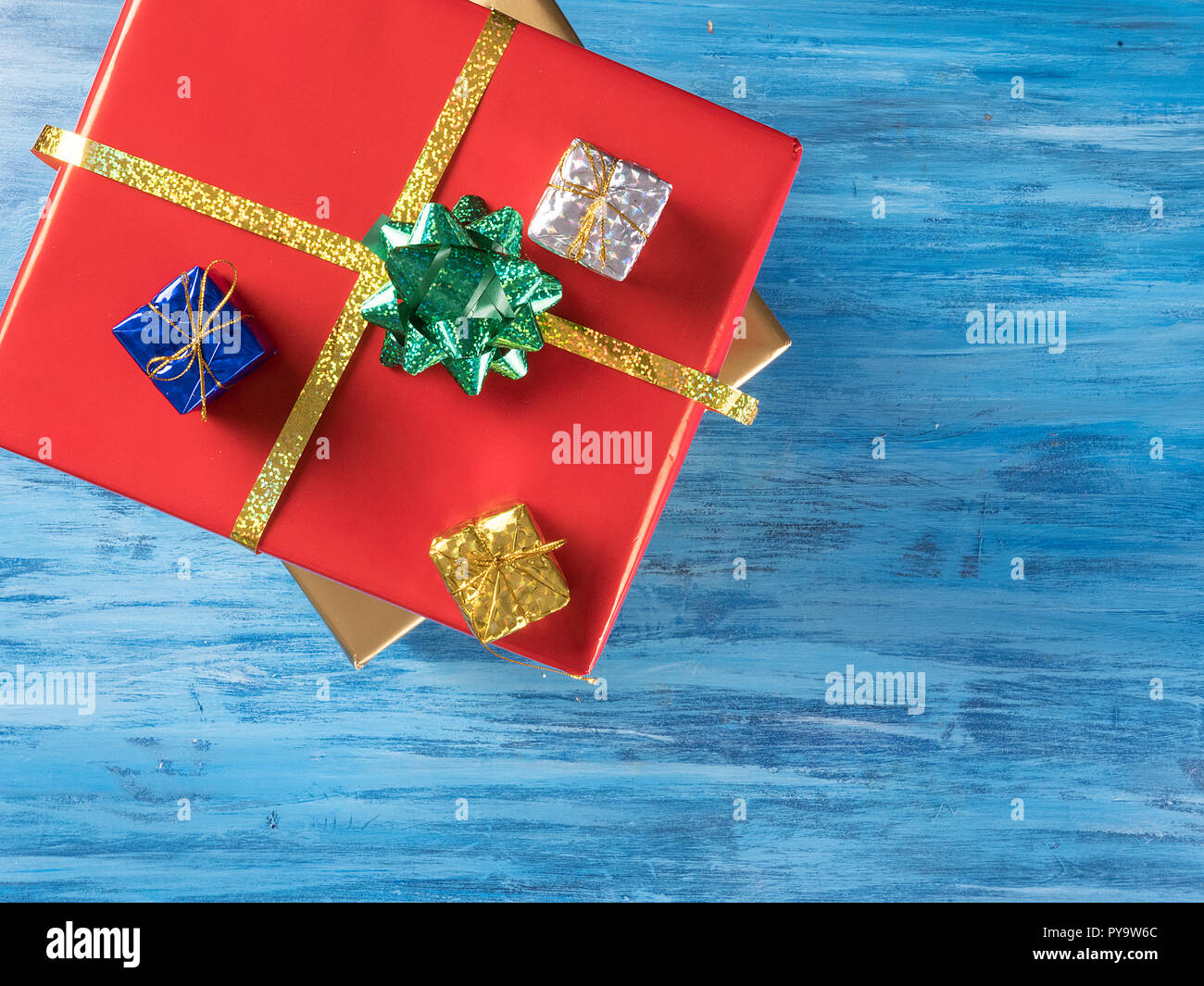 Big Red Christmas gift Box mit kleineren Boxen auf Blue vintage Holz- Hintergrund. Feier Symbol. Stockfoto