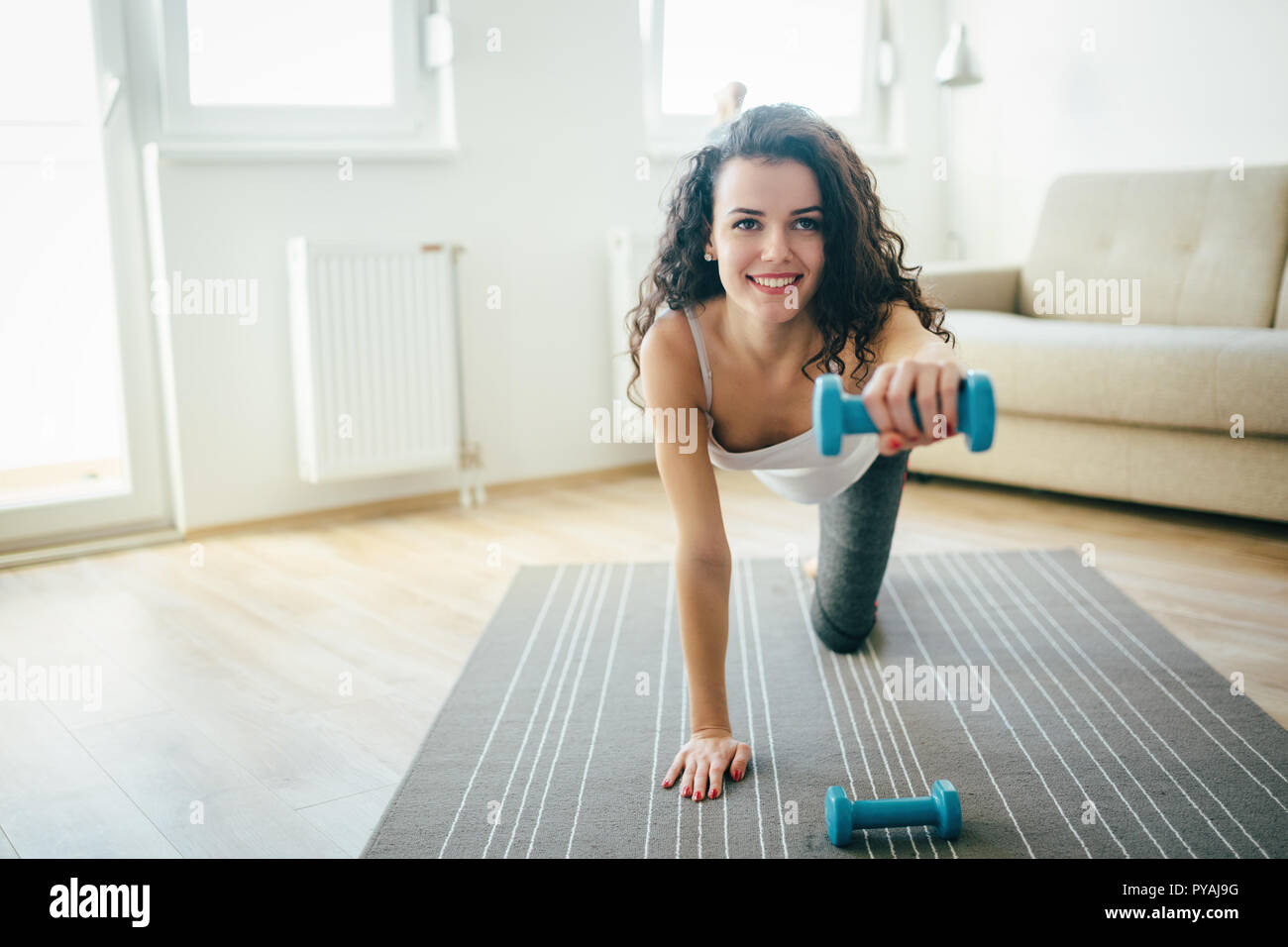 Junge attraktive Sportlerin Übungen zu Hause Stockfoto