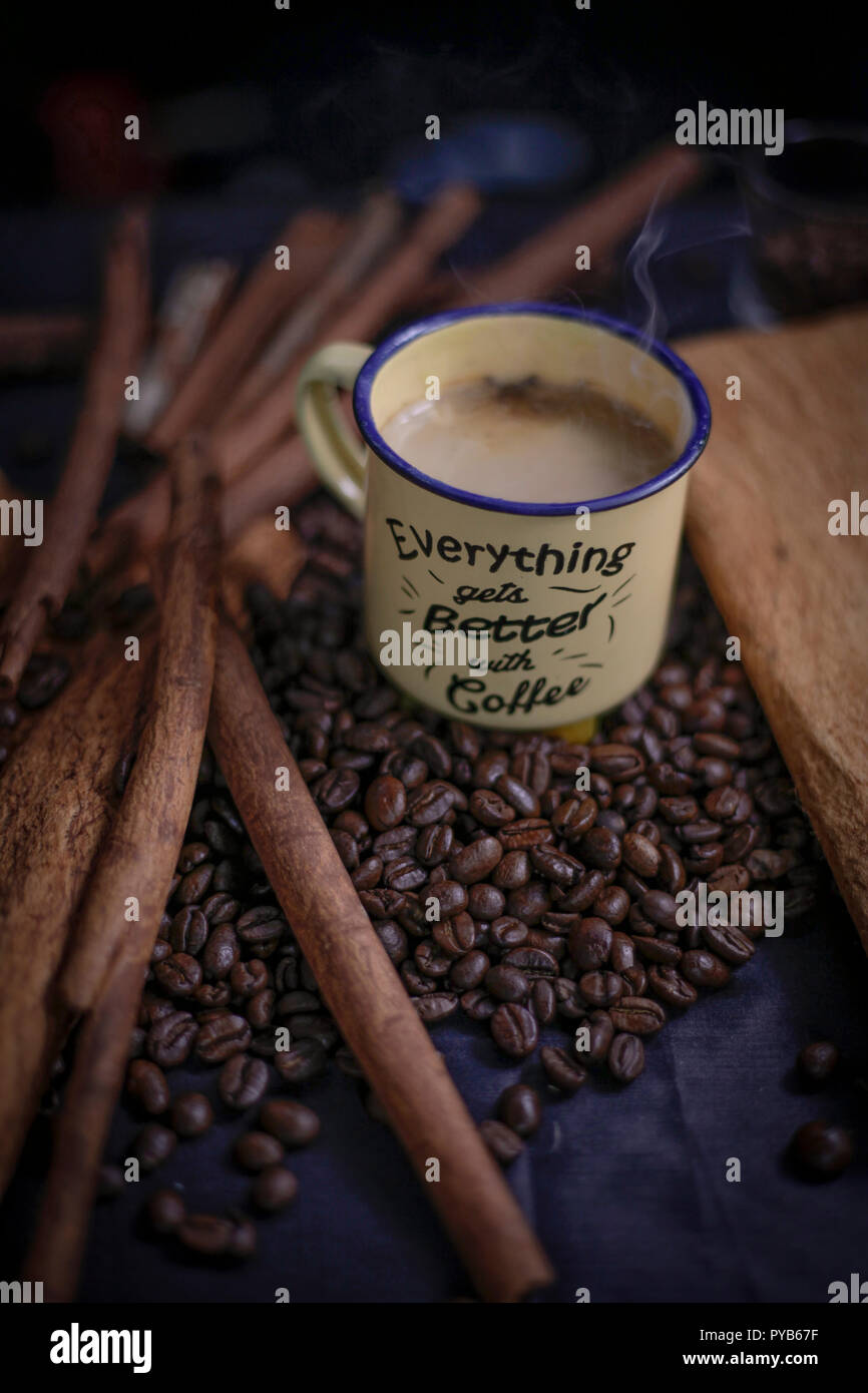 Tasse Kaffee mit Rauch und Kaffeebohnen auf schwarzem Hintergrund Stockfoto