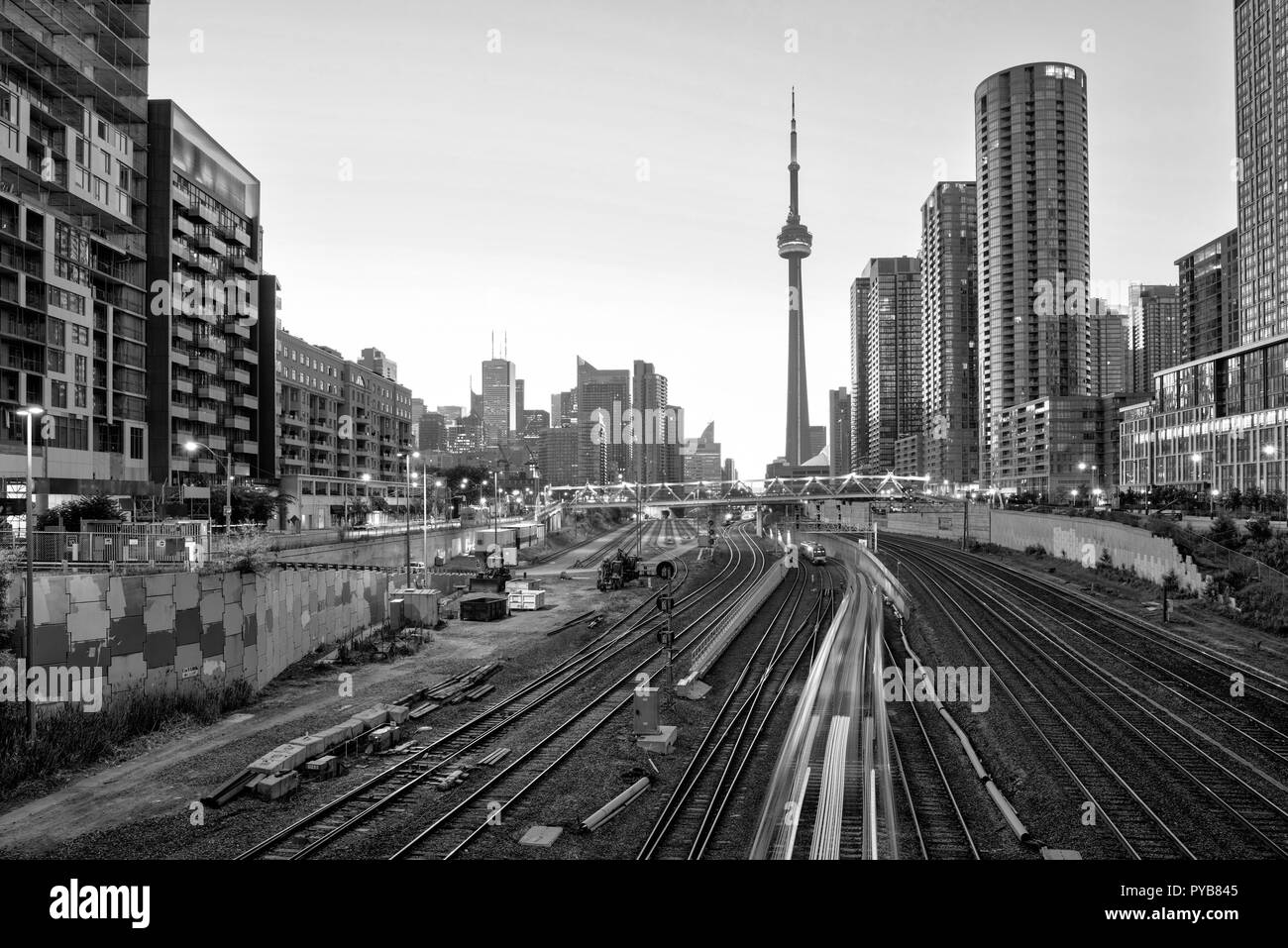 Ein Blick auf Toronto Downtown und dem CN Tower in Schwarz und Weiß über die Brücke mit Gebäuden und Zug bei Sonnenaufgang Stockfoto