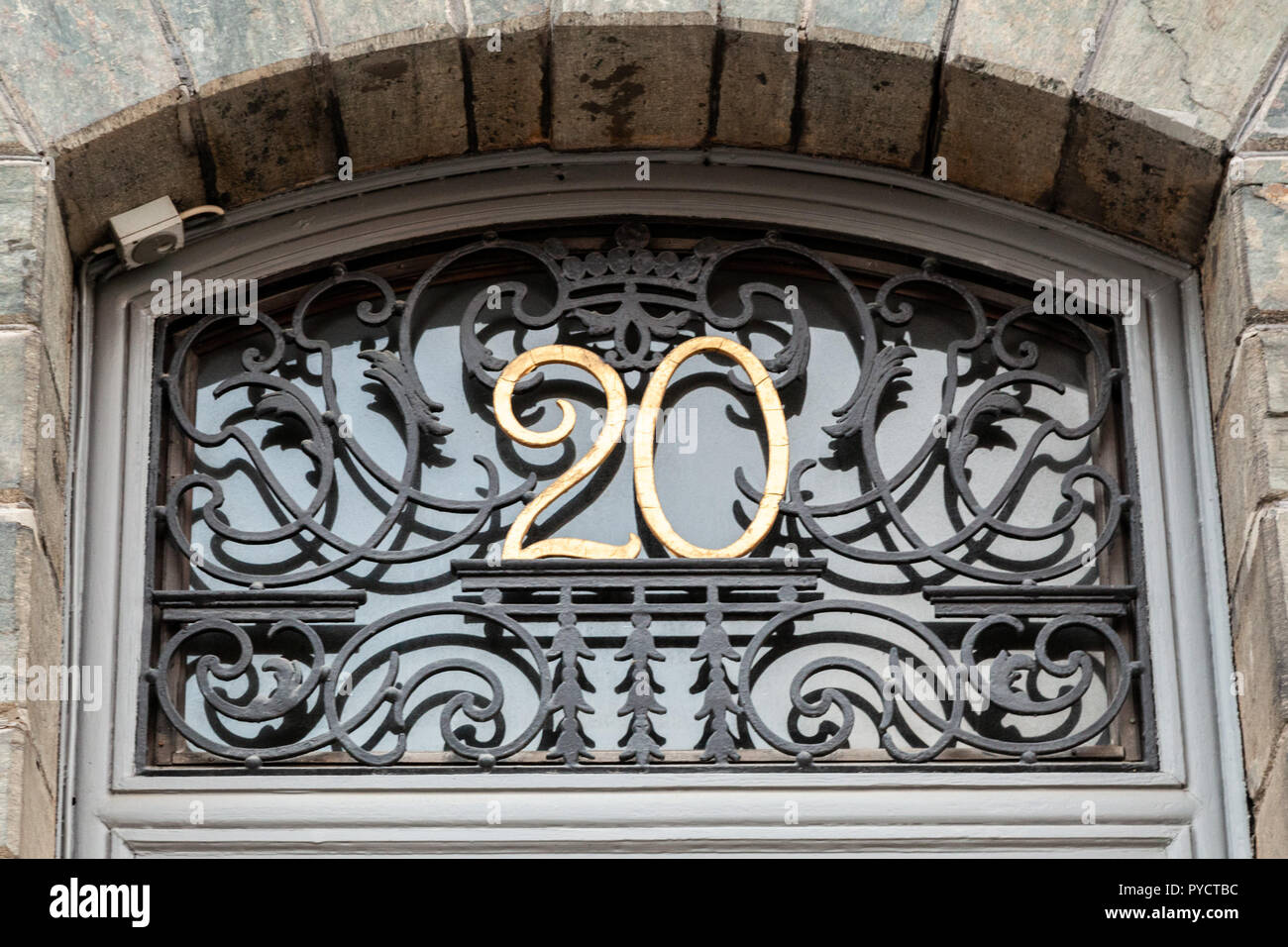 Haus Nummer 20 20 in Designer Schmiedeeisen font einschließlich wirbelt und Krone golden Gelb auf Schwarz metall Base über einer Tür eingefügt Feste lackiert Stockfoto