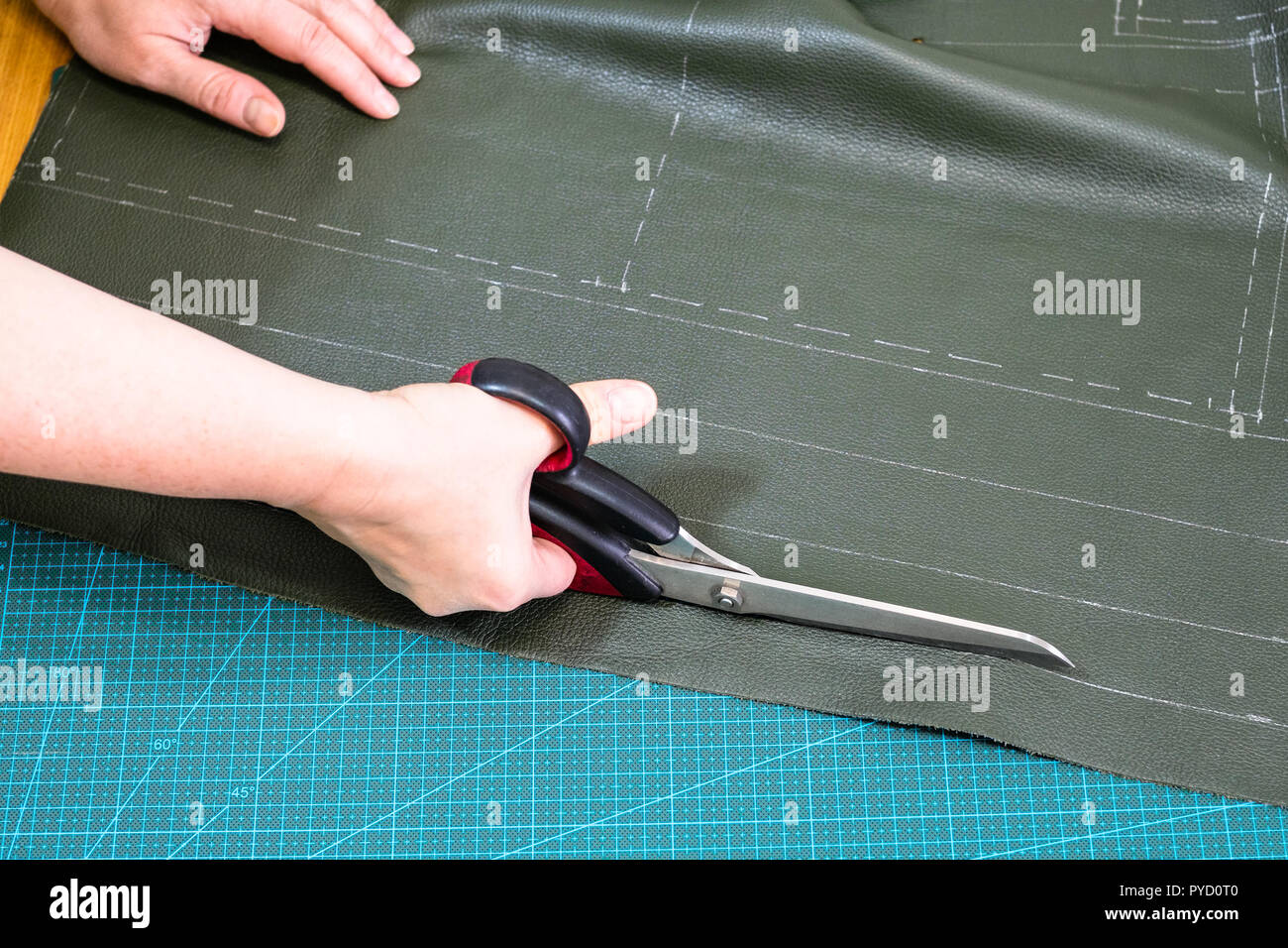 Workshop, Textil und Leder Reisetasche - Handwerker Schnitte Grün Leder mit einer Schere Stockfoto