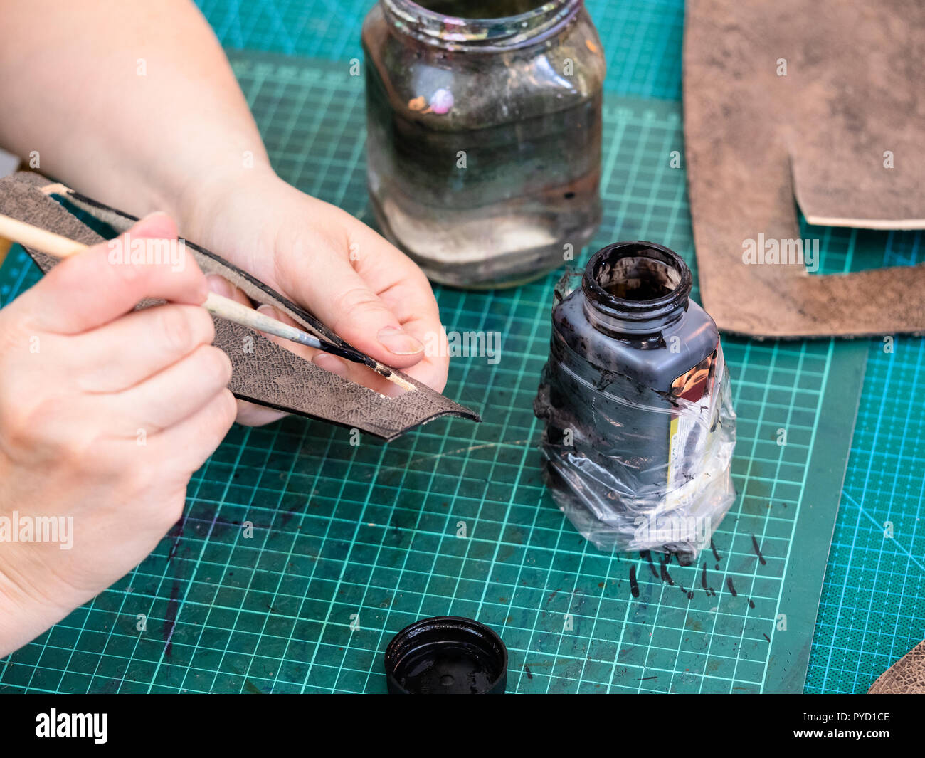 Workshop der geschnitzten Leder Tasche - Handwerker Flecken die Kanten der geschnitzten Leder Los für eine Handtasche Stockfoto