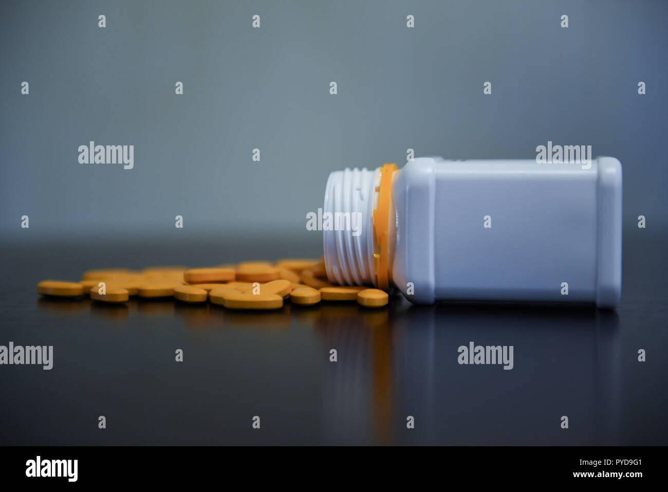 Gelbe Pillen zufällig auf den Schwarzen Tisch mit weißen Pille containr neben Ihnen Stockfoto