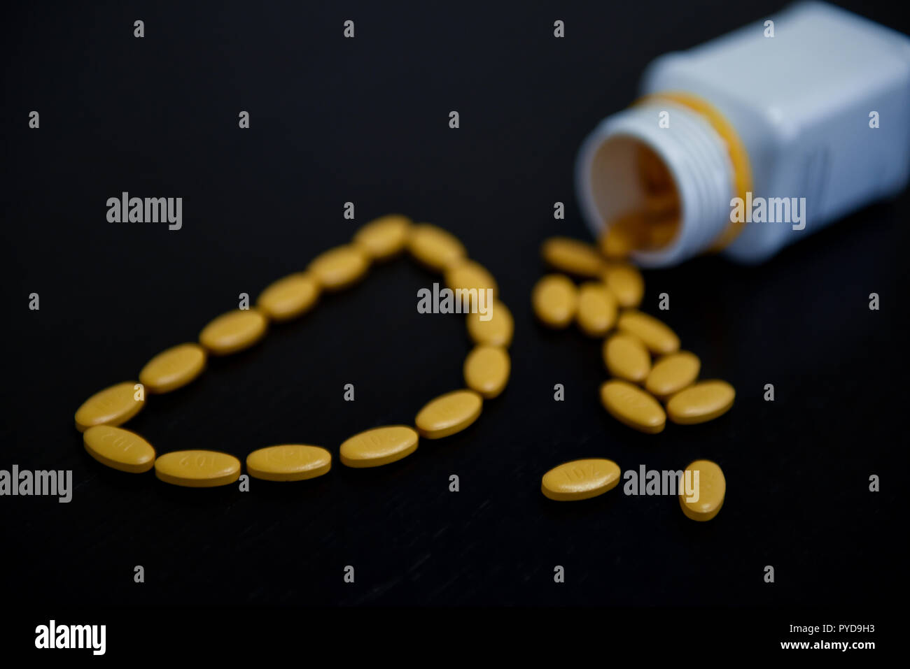 Blick von oben auf die Buchstaben D mit gelben pharmazeutischen Pillen Stockfoto