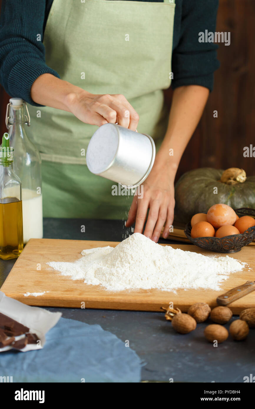 Hände kneten den Teig von Frauen. Der konditor ist ein Ei in das Mehl. Auf dem hölzernen Tisch backen Zutaten. Kürbis Mehl Öl Milch C Stockfoto