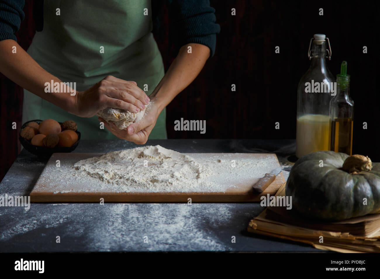 Hände kneten den Teig von Frauen. Backzutaten auf hölzernen Tisch Kürbis Milch Öl Mehl Kopie Raum Stockfoto