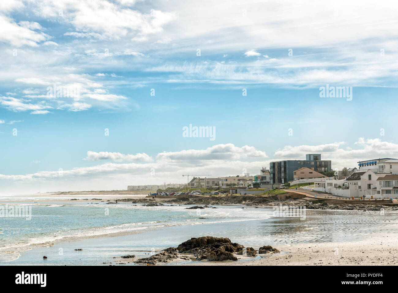 Kapstadt, Südafrika, 14. AUGUST 2018: Ein Strand Szene, mit Apartment Gebäude, Fahrzeuge und Menschen, in Bloubergstrand Stockfoto