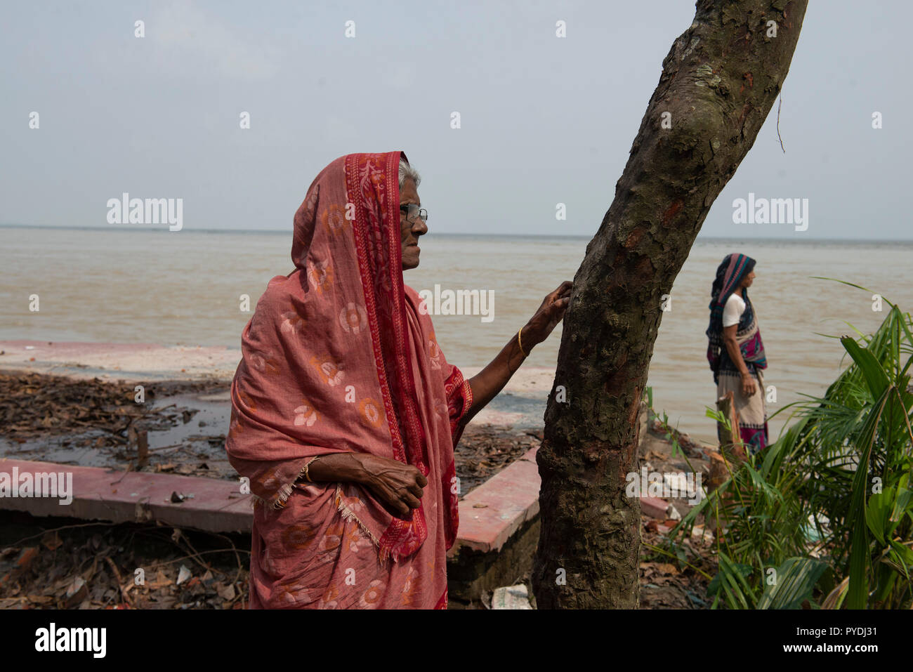 Aysha (links) gesehen stehen neben die Reste ihres nach Hause nach ausgehöhlt wird. Auswirkungen des Klimawandels sind sehr visuell in einem Land wie Bangladesch. Im Jahr 2018, ein schneller Fluss erosion Geschehen rund um die Bereiche neben dem Padma River. Viele Menschen verloren ihre Häuser, Grundstücke und die Art zu Leben. Dieser schnellen Fluss erosion machte viele Klimaflüchtlingen. Stockfoto