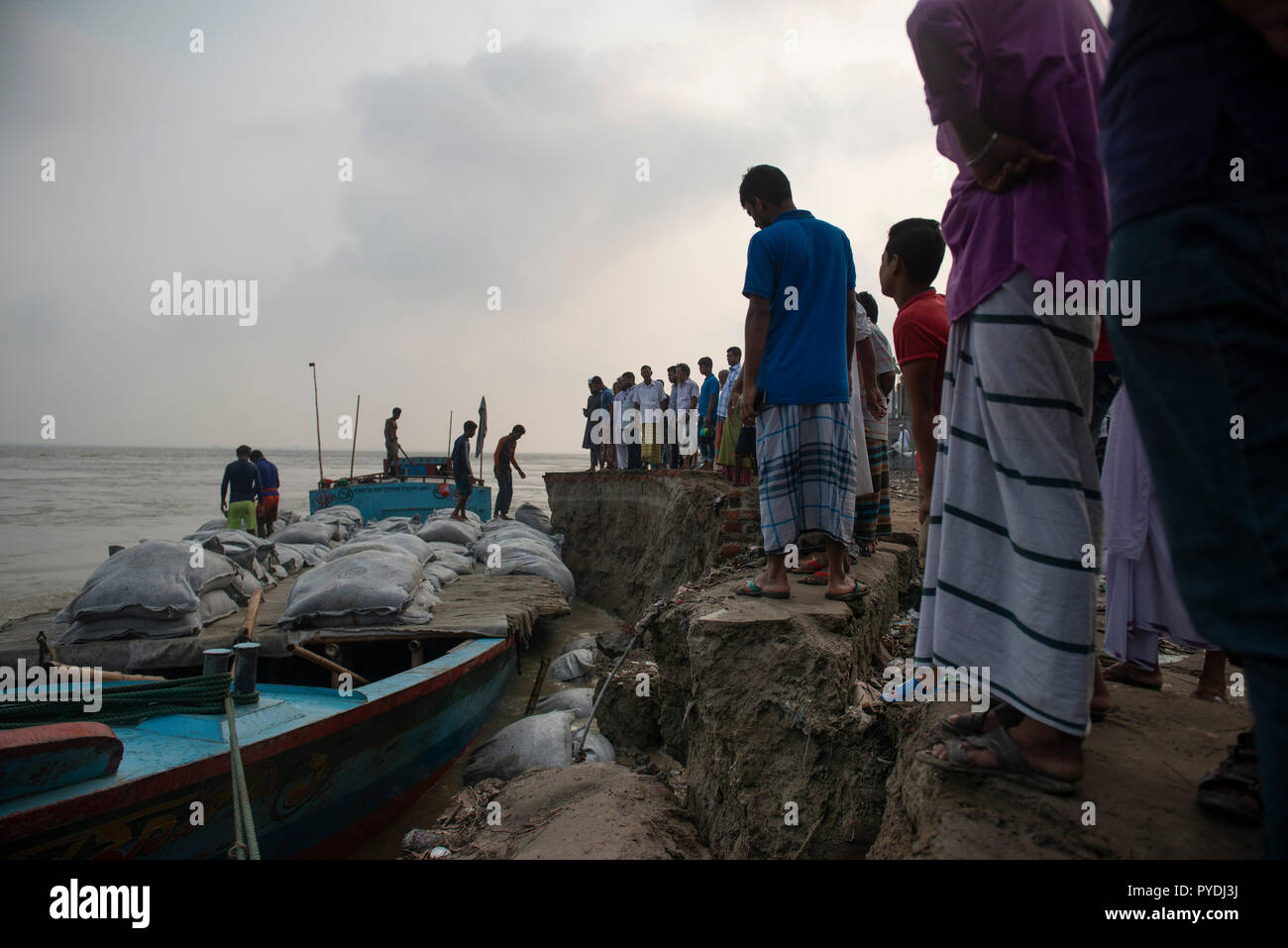 Der lokalen Bevölkerung und Behörden gesehen am Flussufer neben einem Boot mit Sandsäcken verwendet Rapid River Erosion zu stoppen. Auswirkungen des Klimawandels sind sehr visuell in einem Land wie Bangladesch. Im Jahr 2018, ein schneller Fluss erosion Geschehen rund um die Bereiche neben dem Padma River. Viele Menschen verloren ihre Häuser, Grundstücke und die Art zu Leben. Dieser schnellen Fluss erosion machte viele Klimaflüchtlingen. Stockfoto