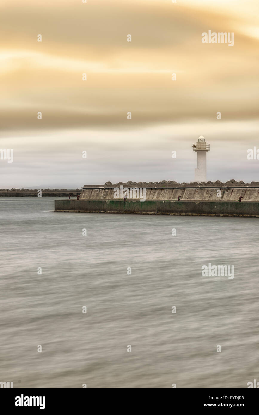 Lange Belichtung geschossen von düsteren windigen Tag am abgeschiedenen Ocean Front mit weißen Leuchtturm Stockfoto