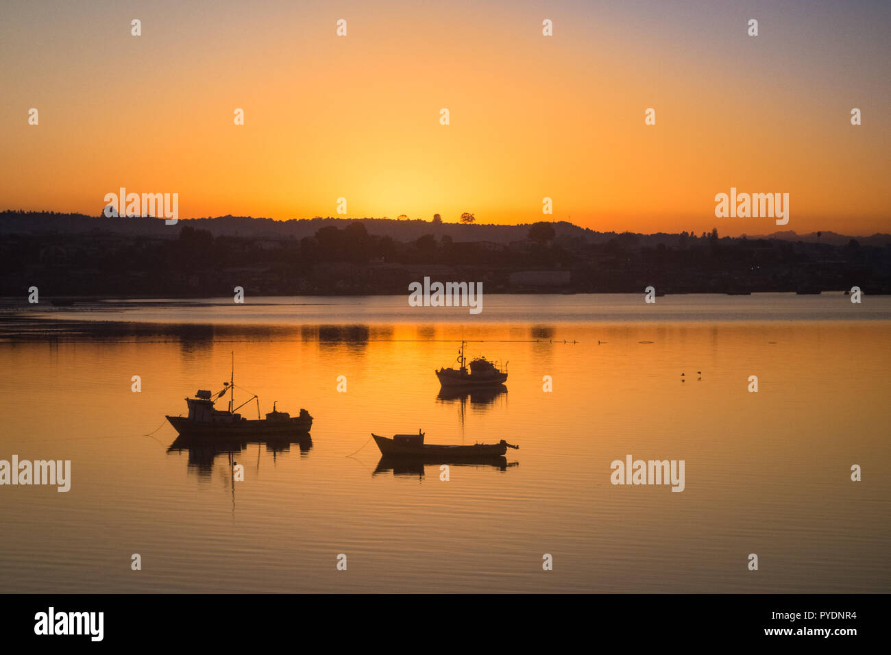 Sonnenaufgang in den Hafen von Quellon in Chiloe Insel, Fischerboote Silhouetten. Patagonien Stockfoto
