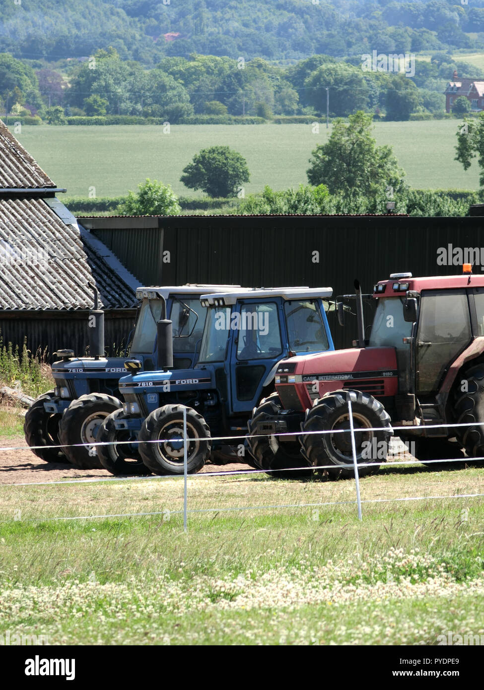 Bei internationalen 5150 & Ford Traktoren der Serie 7610 auf einem Bauernhof, Staffordshire, England, UK im Juni Stockfoto