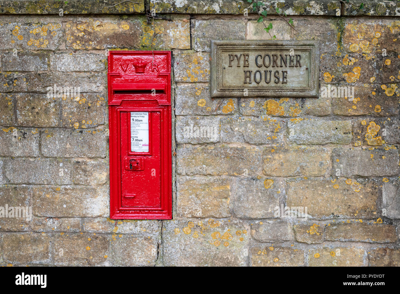 Roter Briefkasten in einer cotswold Steinwand. Broadway, Worcestershire, Cotswolds, England Stockfoto