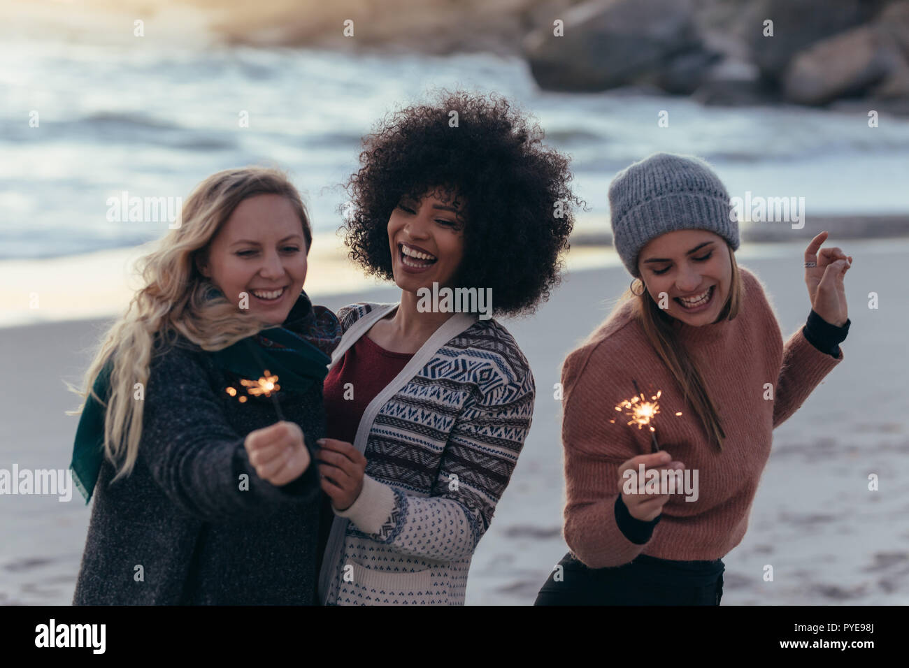 Gruppe von weiblichen Freunde, Spaß mit Wunderkerzen im Freien am Strand. Vielfältige Gruppe von jungen Frauen feiert Tag des neuen Jahres am Strand. Stockfoto