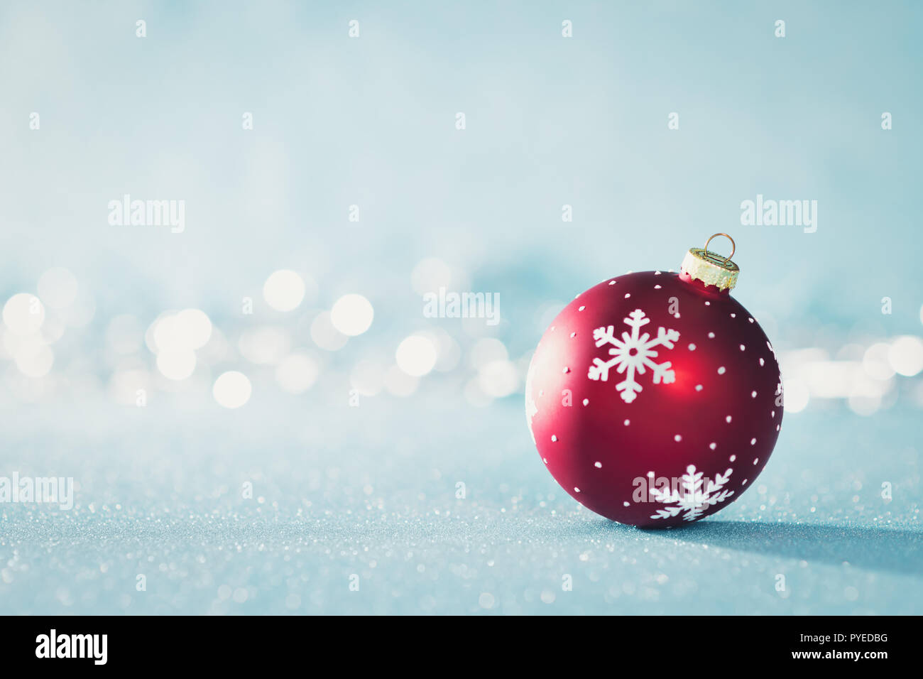 Leuchtend rote Weihnachtskugel im Winter Wonderland. Blau Weihnachten Hintergrund mit Defokussierten Weihnachtsbeleuchtung und Kopieren. Stockfoto