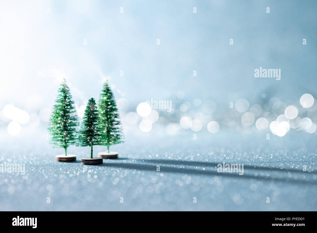 Magische Miniatur Wunderland Hintergrund. Evergreen Weihnachtsbäume auf glänzenden blauen Hintergrund mit Bokeh. Stockfoto