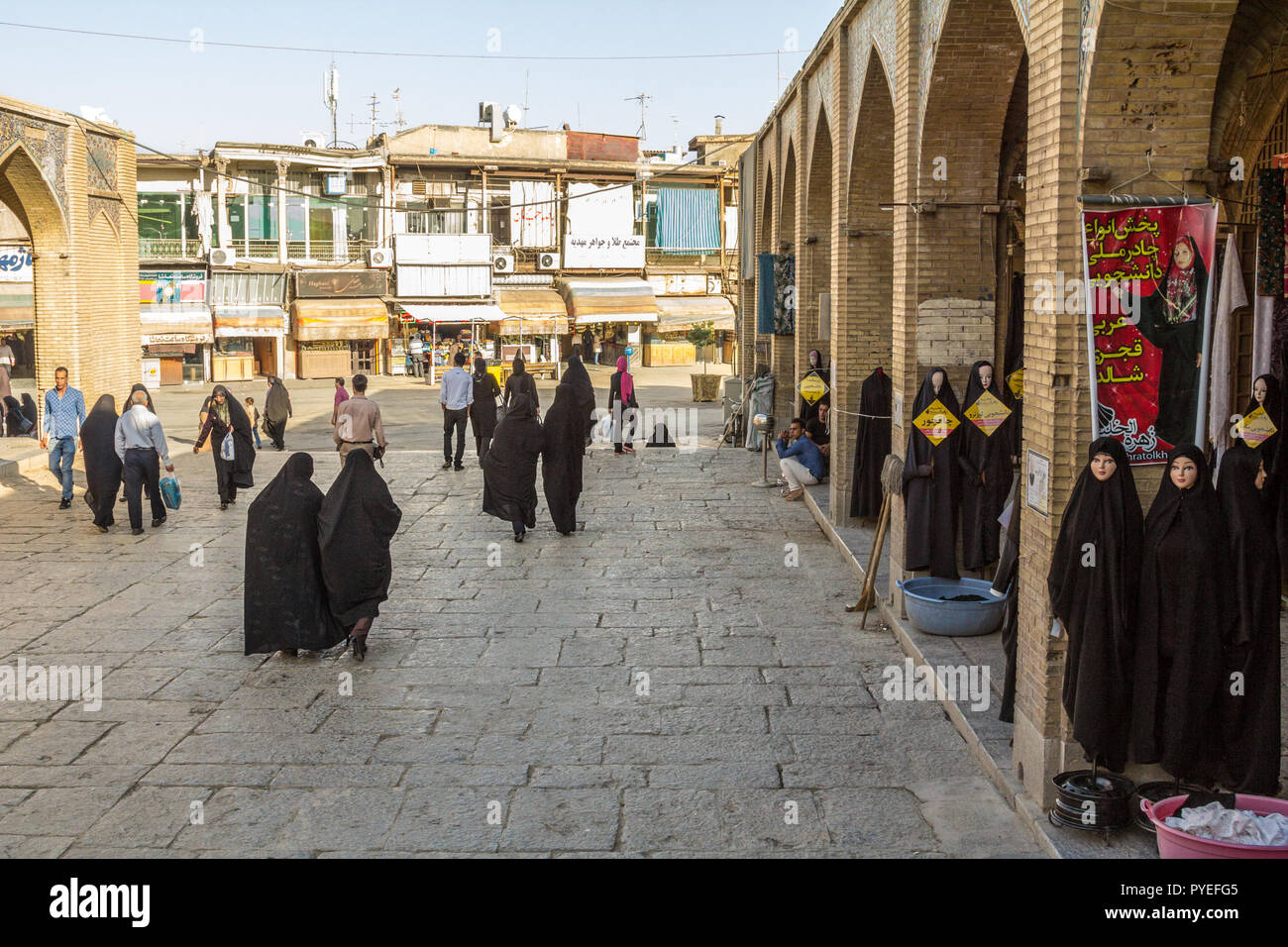 ISFAHAN, IRAN - 20. AUGUST 2016: Frauen in islamischen Bescheidene Kleidung vorbei an den Geschäften der Islamischen outfit Verkäufer schwarzes Kopftuch, Schleier und Stockfoto