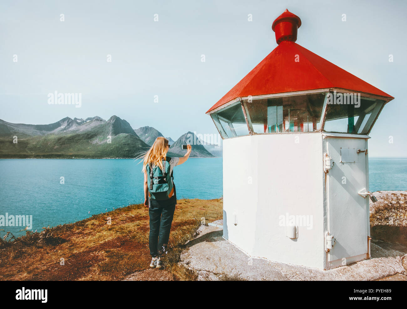 Frau touristische Blogging mit Smartphone, Foto in der Nähe Leuchtturm Reisen lifestyle Abenteuer Sommer reise Outdoor in Norwegen Stockfoto