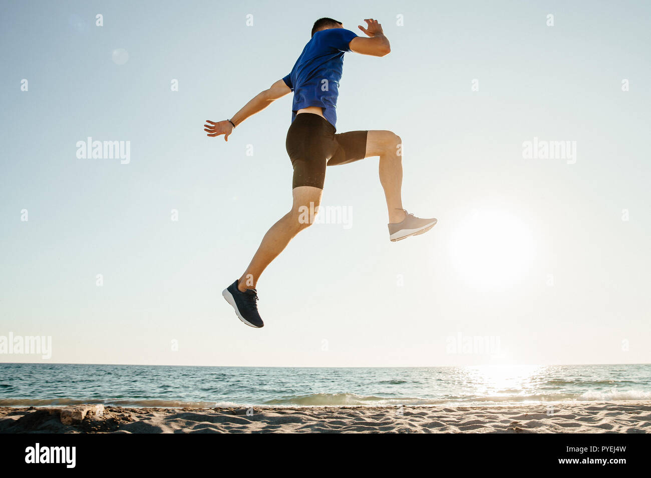 Männliche Athlet springen auf und fliegen in der Sonne am Strand. Stockfoto