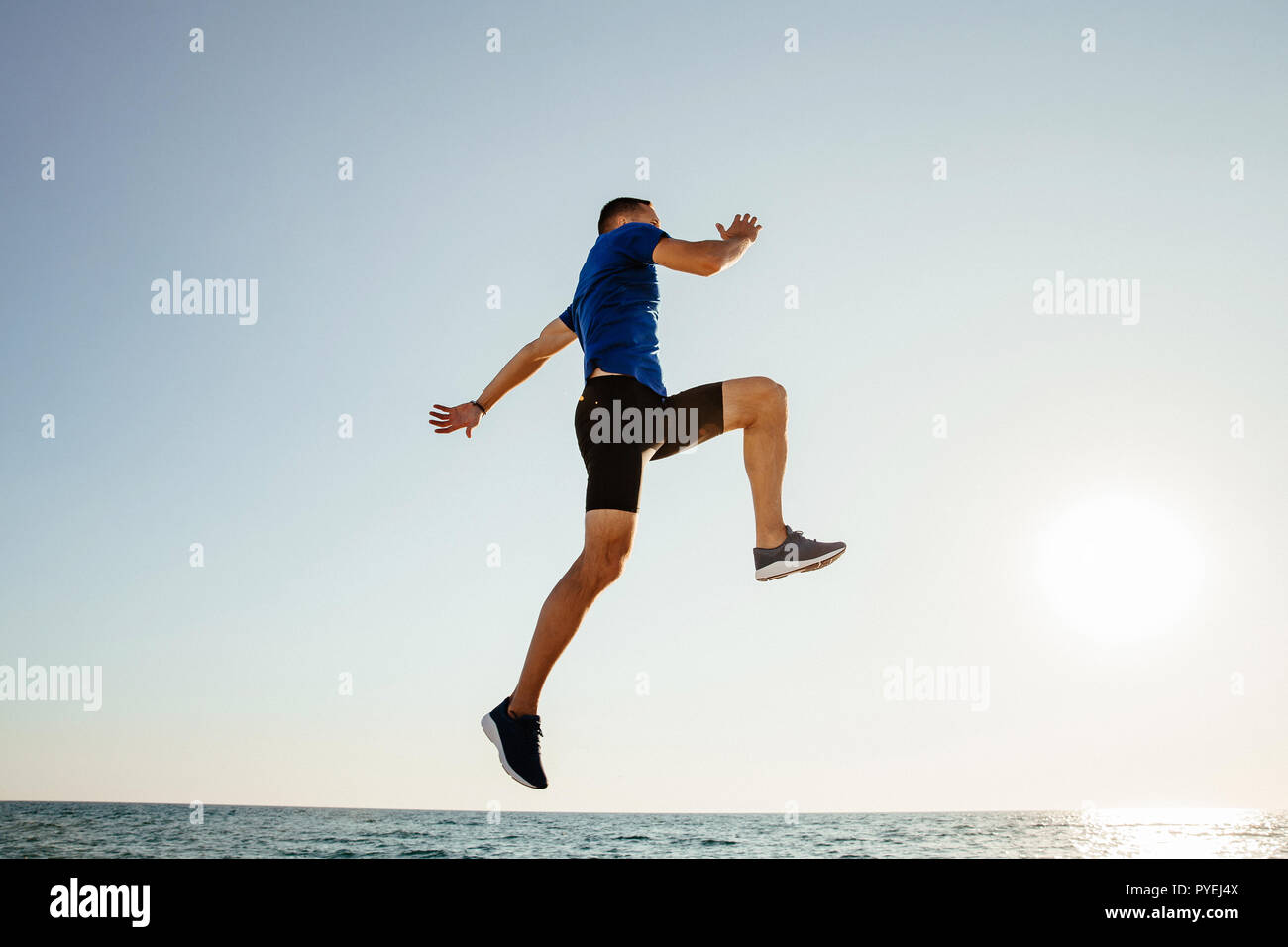 Mann springen auf und fliegen im Sonnenlicht über Meer Stockfoto
