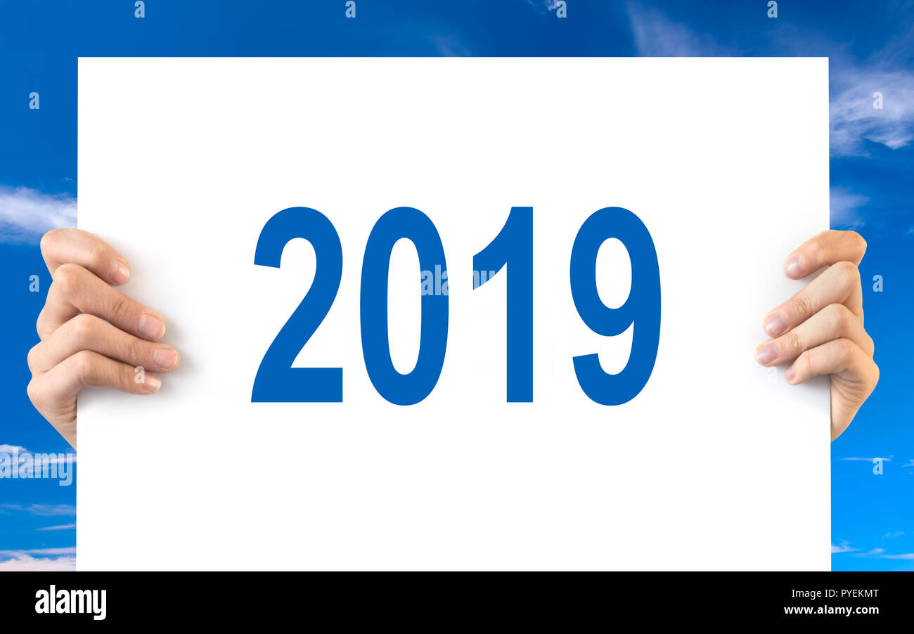 Hände halten eine weiße Tafel mit 2019, blauer Himmel Stockfoto