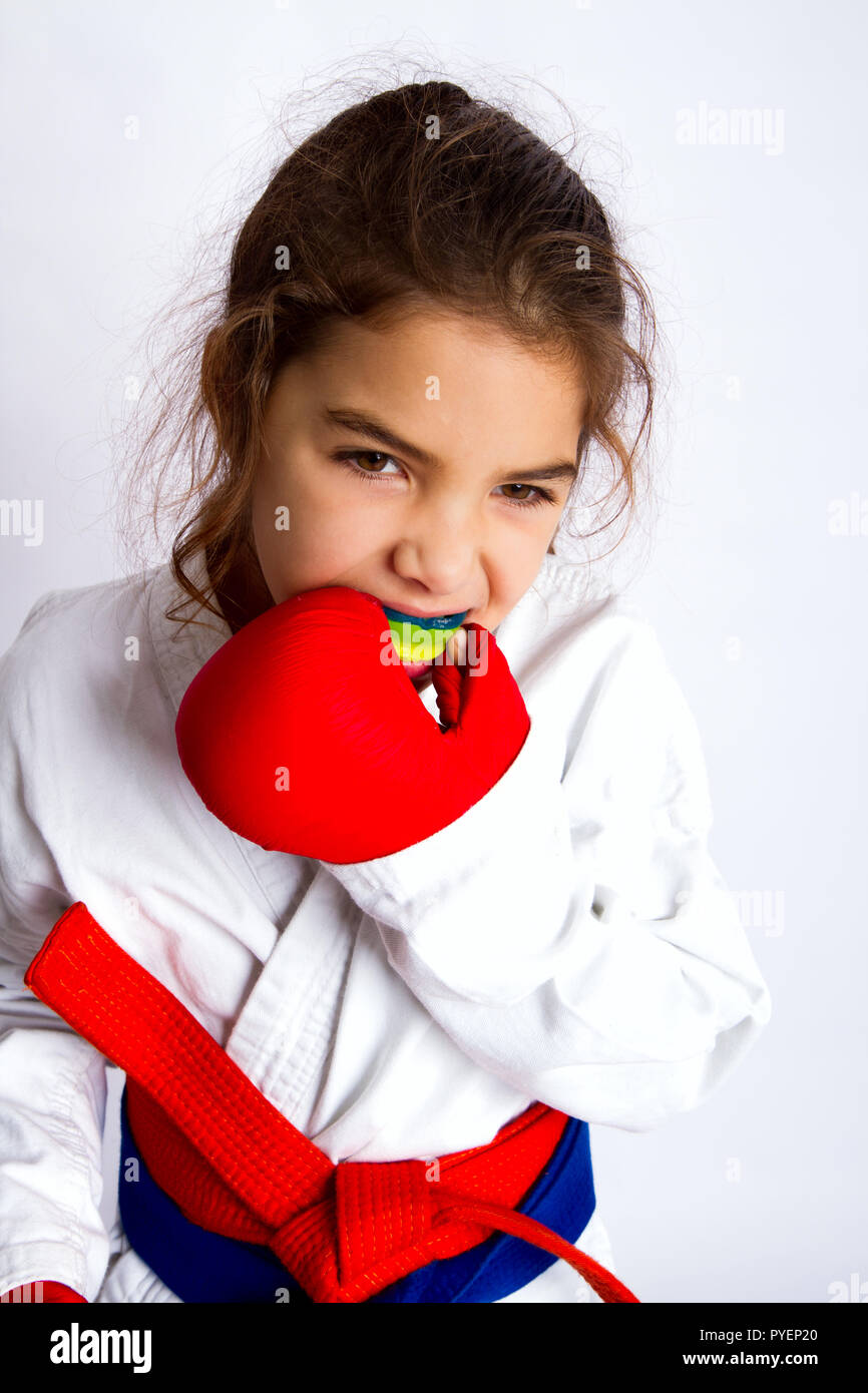 Ein wenig Karate Mädchen im weißen Kimono und in einer roten und blauen Gürtel gleichzeitig setzt auf den Mund, Guard in Vorbereitung auf den Kampf. Stockfoto