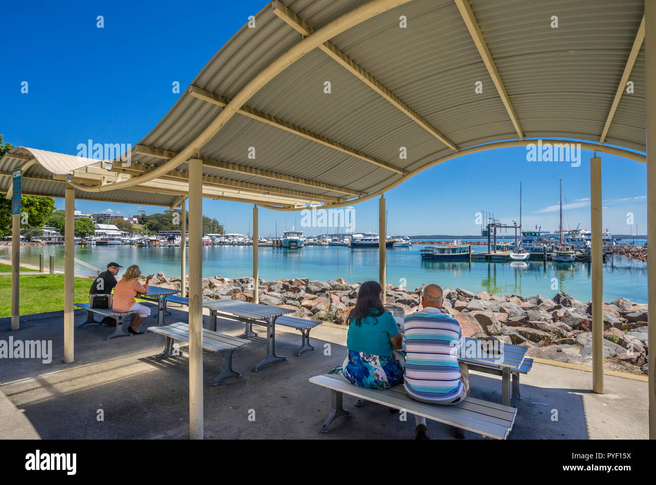 Picknick-tische in Nelson Bay Vorland finden mit Blick auf die Marina und Wharf, Port Stephens, Hunter, New South Wales, Australien Stockfoto