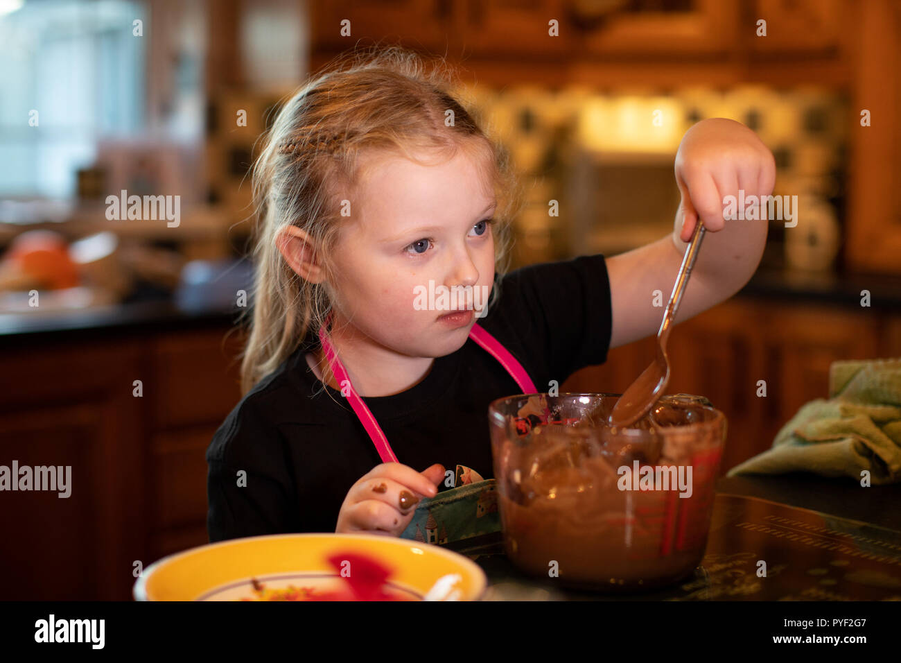 Kleines Mädchen schmilzt die Schokolade zu Halloween Festlichkeiten Stockfoto