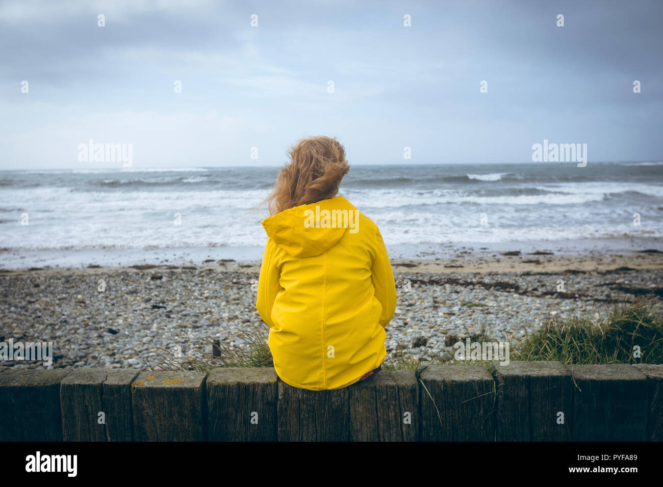 Frau sitzt auf dem Zaun im Strand Stockfoto