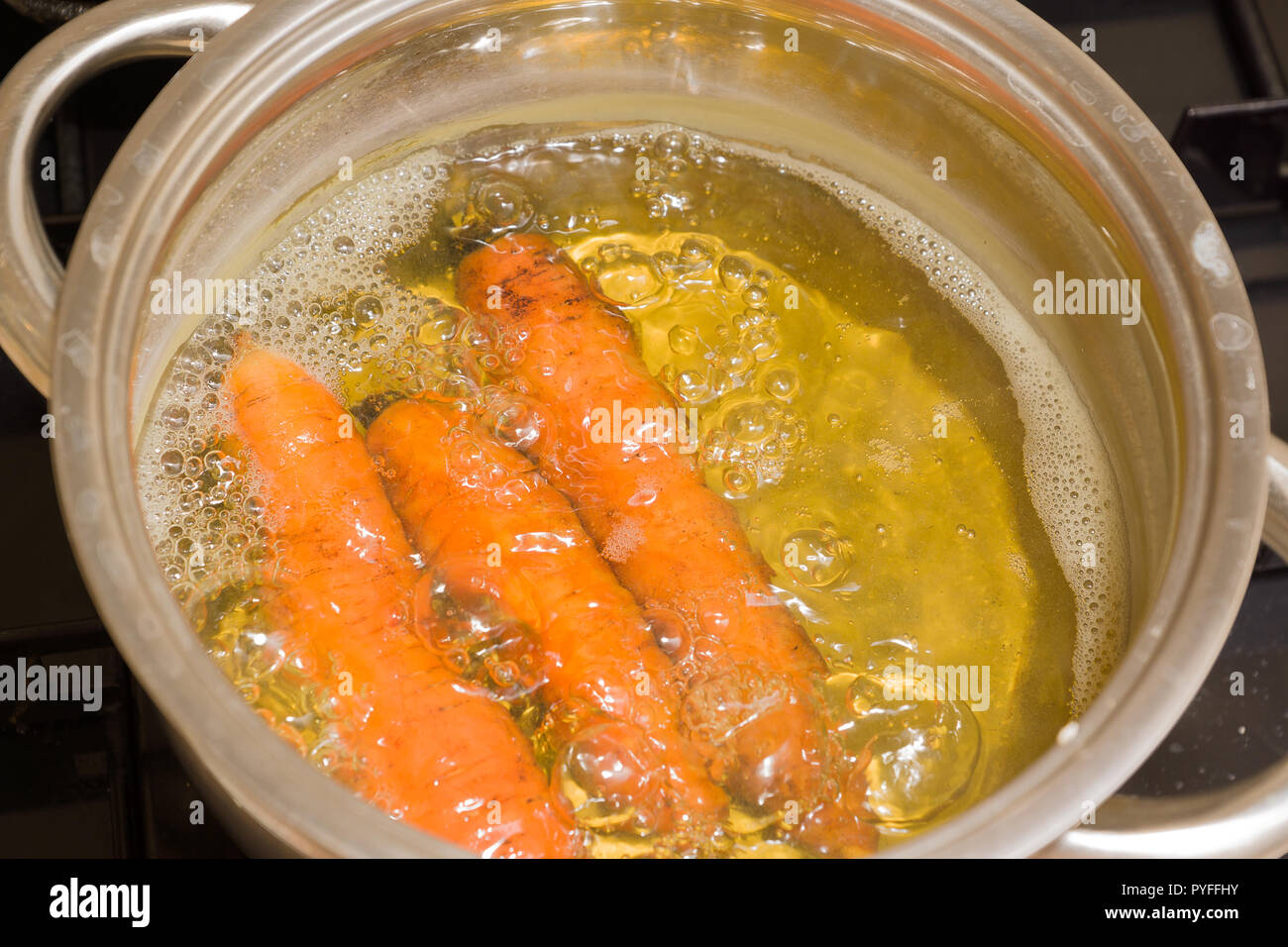 Rohe Karotten sind in einen Topf mit kochendem Wasser gekocht Stockfoto