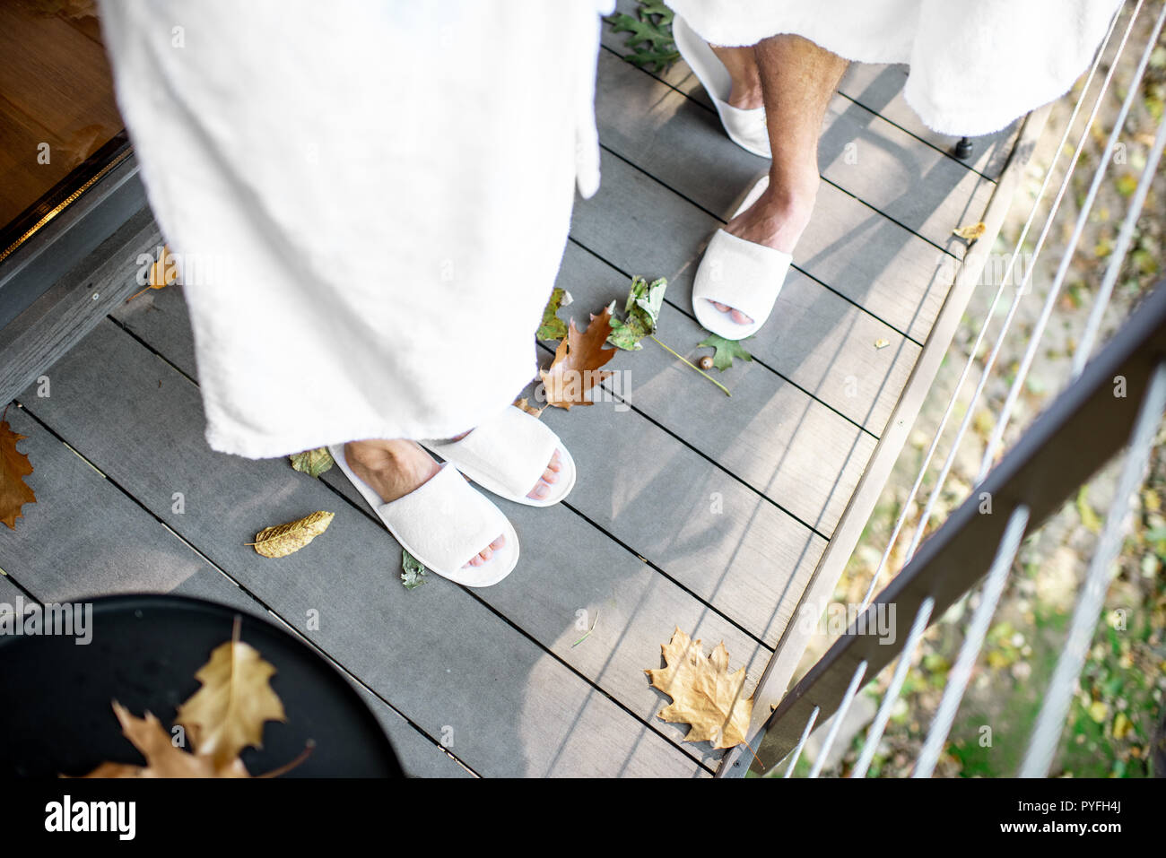 Paar in Bademantel und slipppers stehen auf der Terrasse mit schönen Blätter im Freien. Sicht von oben mit kein Gesicht Stockfoto